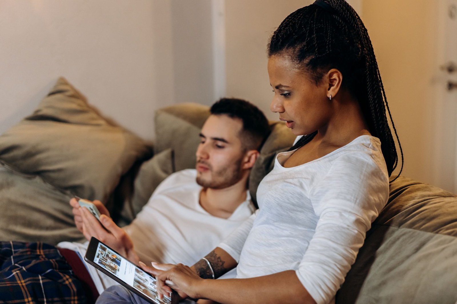 Two homeowners on a sofa looking at a phone and a tablet