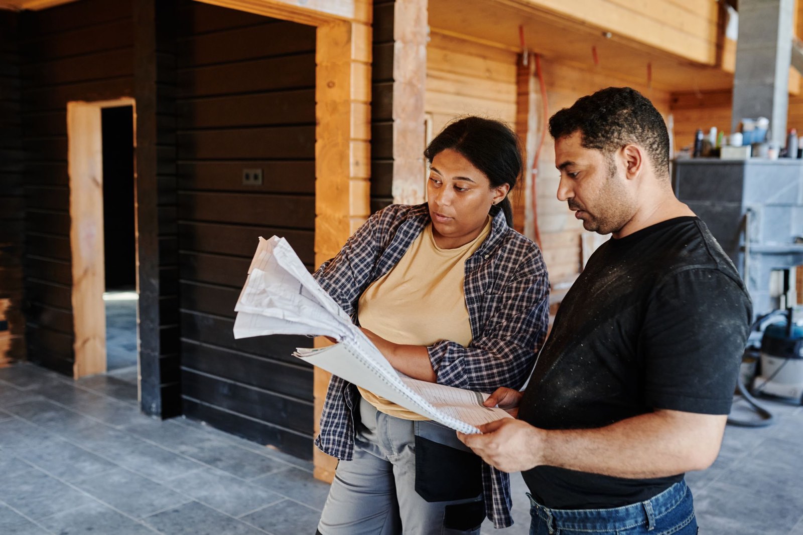 Two people going over plans inside a house under renovation