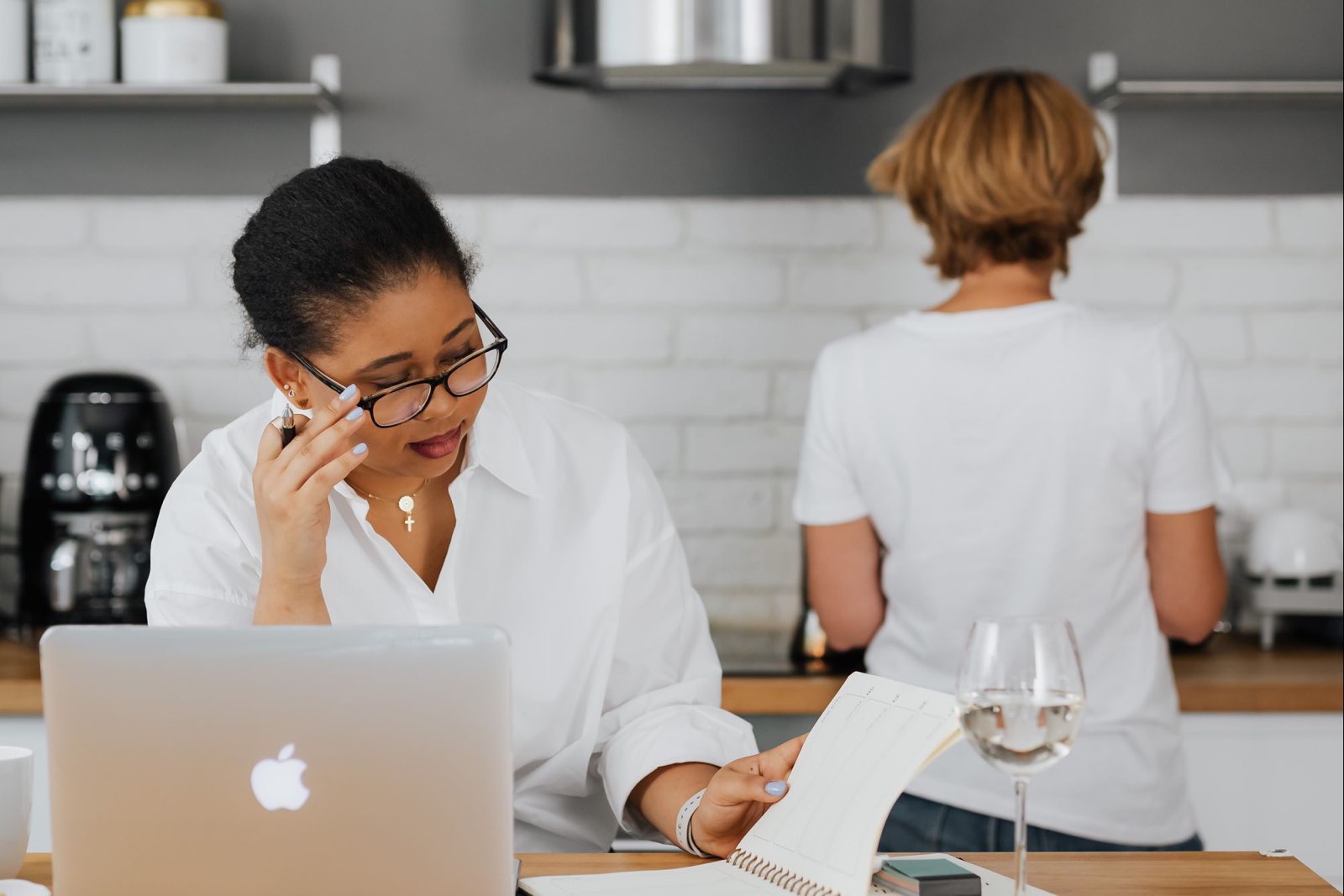 A homeowner at a laptop in her kitchen, phone in hand