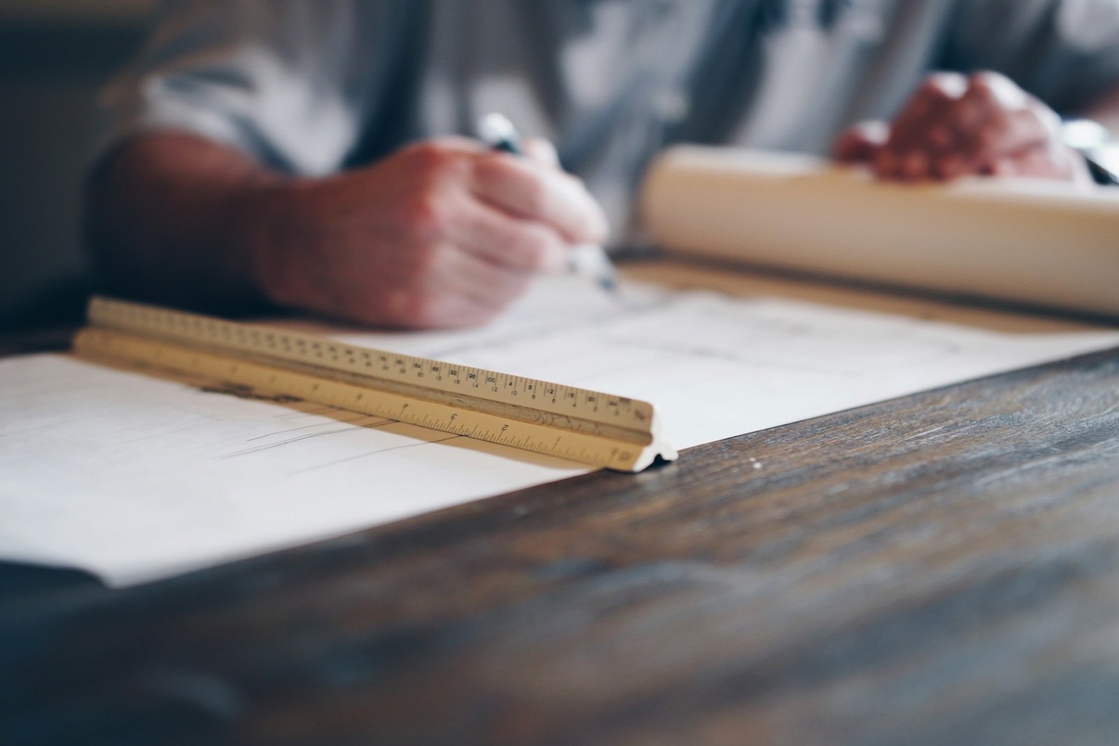 A hand drawing on a plan with a pencil and a scale ruler