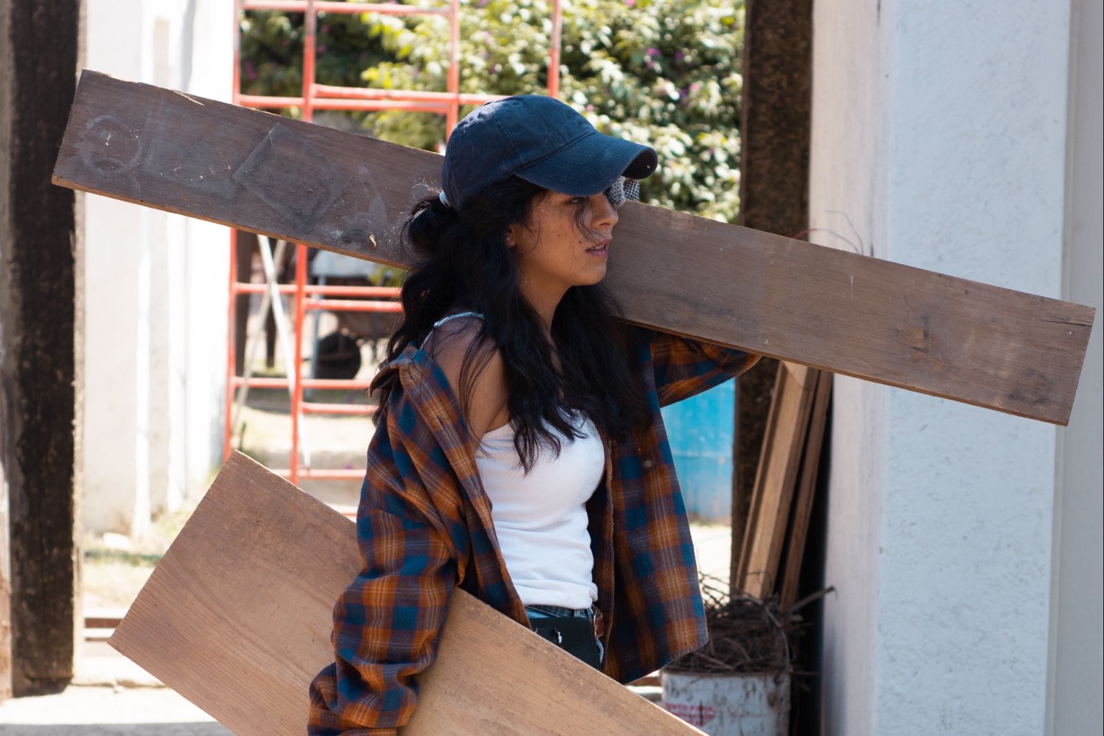 A carpenter carrying wooden boards across a job site