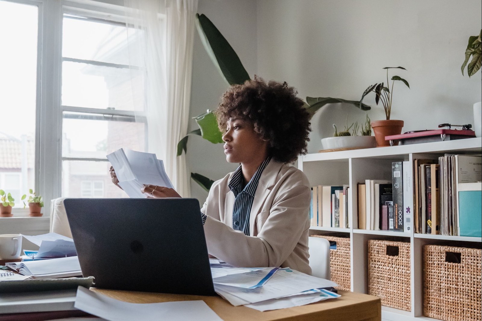A bookkeeper working through paperwork at a laptop in a home office