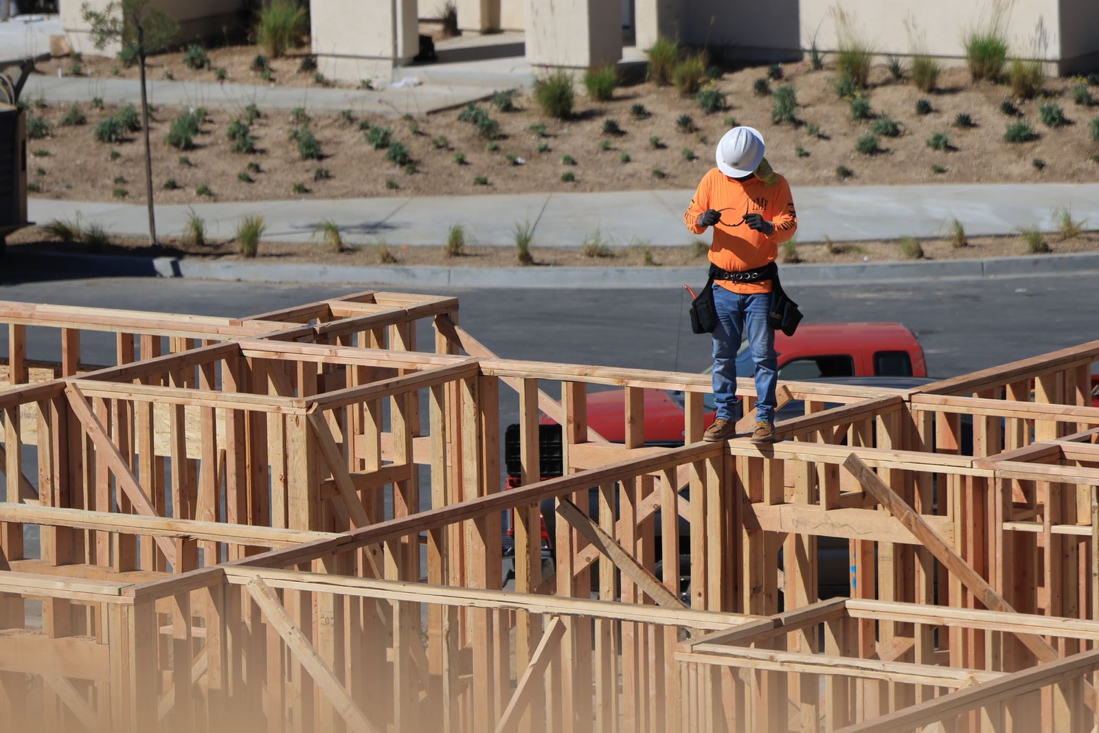 A worker on a timber frame checking a device on site